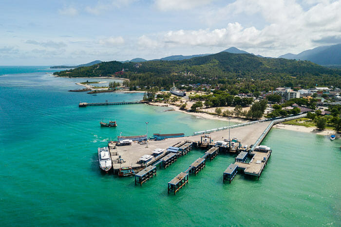 Drone shot of Thong Sala Pier on Koh Phangan with island in background.