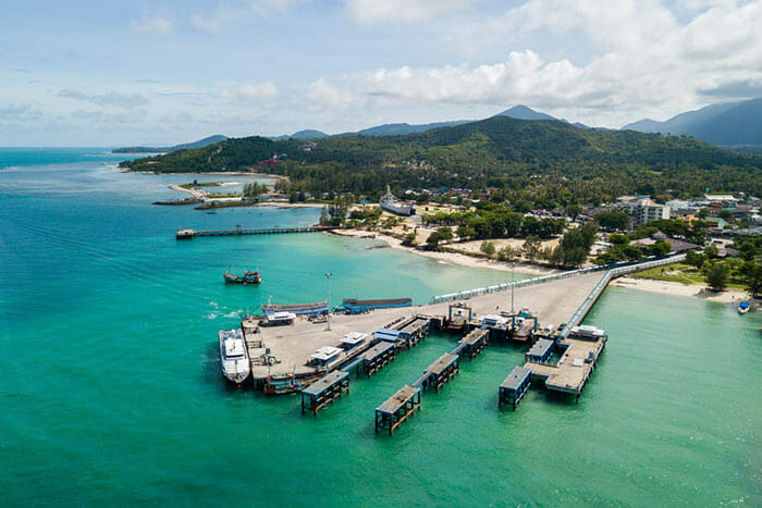 Drohnenaufnahme des Thong Sala Pier auf Koh Phangan mit Insel im Hintergrund.