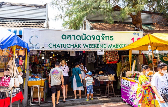 Chatuchak Weekend Market with people, stalls and a big Sign