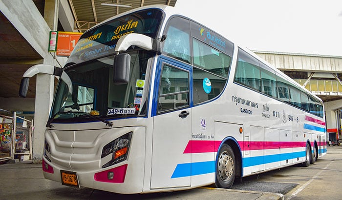 Sombat Tour Bus parked at Bangkok Southern Terminal, displaying distinctive blue and purple stripes, operating between Phuket and Bangkok.