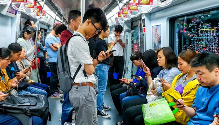 Chinese people looking at their mobile phones inside a subway train