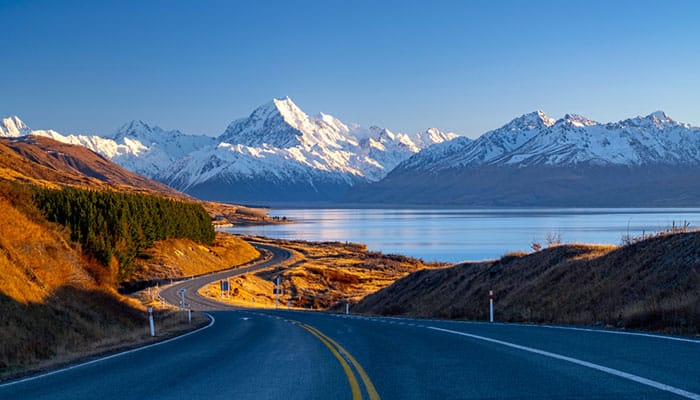 Scenic winding road along Lake Pukaki to Mount Cook National Park, South Island, New Zealand during cold and windy winter morning.