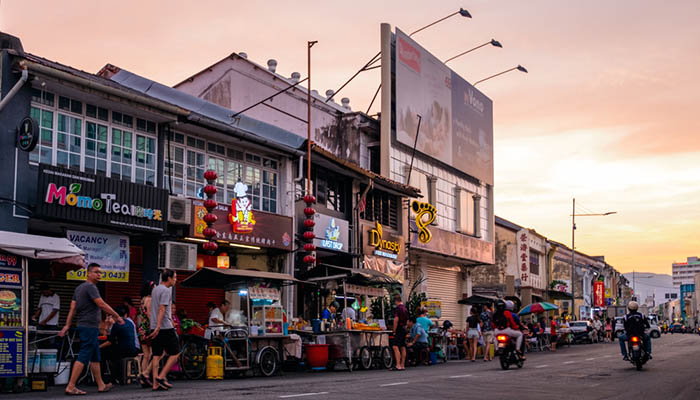 Sunset scene at Chulia Street Night Hawker Stalls. People are eating and shopping around the streets.