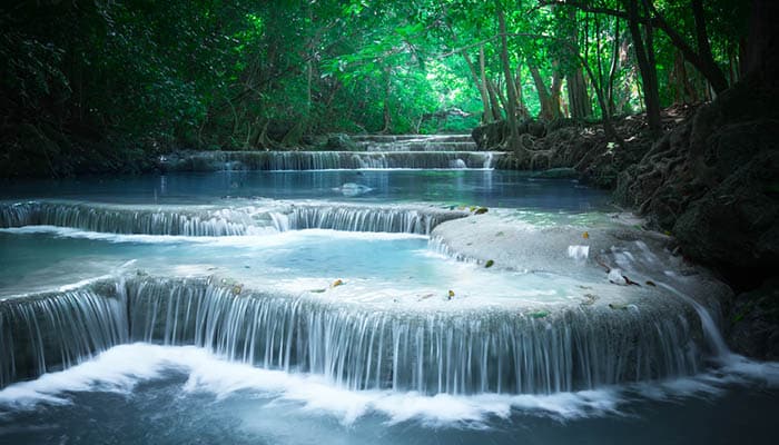 Jungle landscape with flowing turquoise water of Erawan cascade waterfall at deep tropical rain forest. National Park Kanchanaburi, Thailand