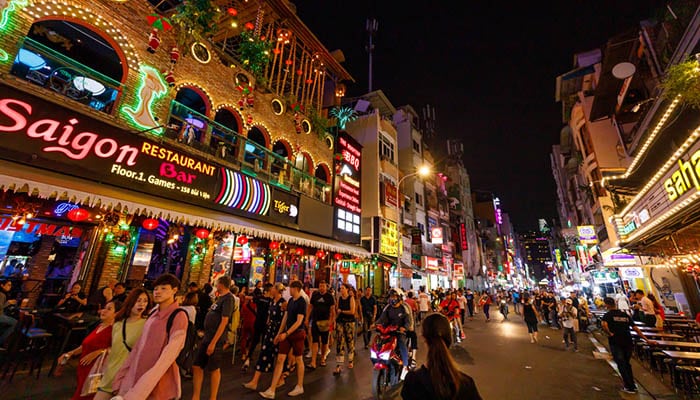 Busy bar street in Ho Chi Minh. Nightime with neon lights and many people