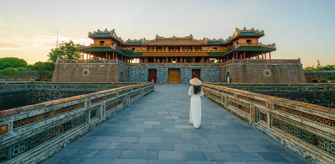 Ngo Mon gate - the main entrance of forbidden Hue Imperial City in Hue city, Vietnam, with Vietnamese girl wearing traditional dress Ao Dai