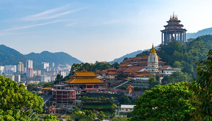 Kek Lok Si Temple in Georgetown Penang, Malaysia during daylight - A majestic Buddhist temple with multiple tiers and colorful roofs surrounded by lush greenery and overlooking the cityscape.