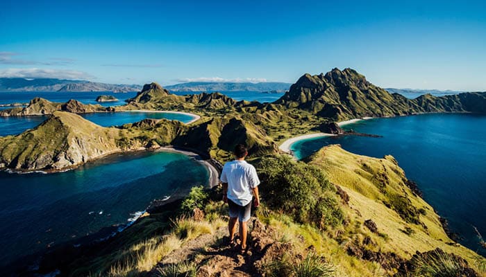 A man stands on a mountain top with beautiful view of oceans and islands at Padar Island, Labuan Bajo