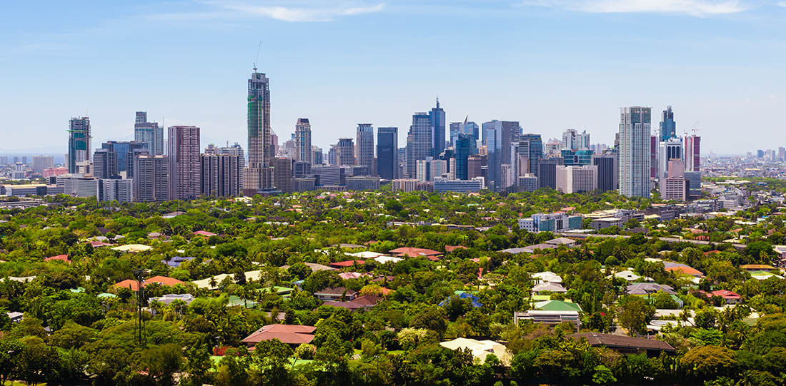 Manila skyline with a lot of green areas in front of the tall buildings, Philippines.