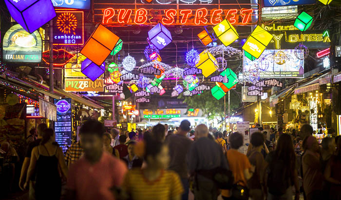 Tourists stroll along Pub Street in Siem Reap. Evening with a lot of bright lights and signs.