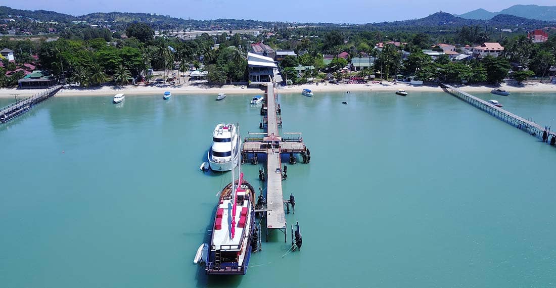 Aerial view of Bangrak Pier, Koh Samui, with ferries and turquoise waters.