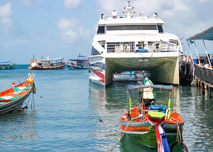 Lomprayah High-Speed Catamaran docked at Mae Haad Pier in Koh Tao with colorful local boats in the foreground.